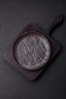 Empty black ceramic plate on a dark concrete background photo