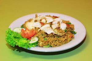 A plate of Nasi Goreng with rice, vegetables, and an egg on top photo