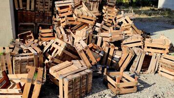 Stack of empty wooden crates leans against a building wall. Crates display signs of disarray and wear, showcasing a rustic, weathered charm video