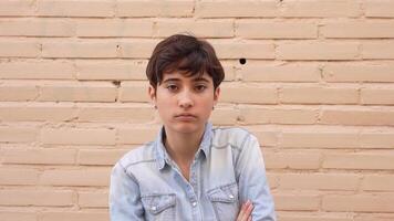 A thoughtful and introspective portrait of a teenager posed against a neutral wall setting video