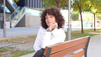 A Thoughtful Woman Sitting Alone on a Comfortable Bench in a Lively Urban Park Setting video