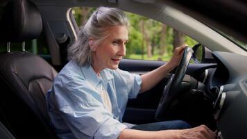 Joyful active smiling Caucasian aged lady woman elderly female senior dealership testing client grandmother auto buyer car driver inside automobile turn on music dancing sing song audio system dance video