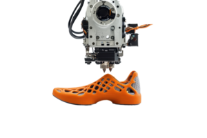 A 3D printer is preparing to create an orange, intricately designed shoe with a lattice structure. png