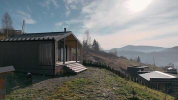 Modern Cabin with Porch Overlooking Hills. A stylish wooden cabin featuring a covered porch, set on a hillside with panoramic views of misty mountains and open skies. video