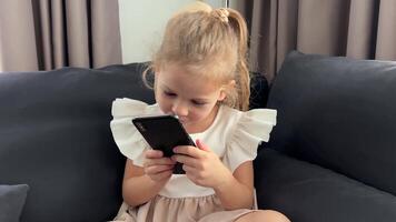 Girl sitting on a sofa at home and using a smart phone. High quality 4k footage video