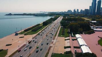 Lakefront Drive and Chicago cityscape by Lake Michigan. Aerial view of Lakefront Drive in Chicago with cars, green spaces, and a scenic view of Lake Michigan and the city skyline on a clear day. video
