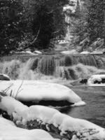 Waterfall in a Snowy Landscape with Tree Branches and Fluvial Features photo