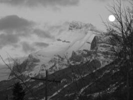 Mountain Landscape with Clouds, Snow, Moon, and Sunlight photo