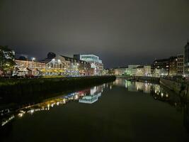 Midnight Cityscape Reflection with Tower Blocks and Clouds Over Lake photo