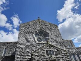 Clouds and Blue Sky Reflected in a Window of a Brick Building Surrounded by Trees photo
