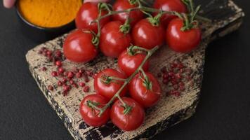 Branches of ripe red cherry tomatoes with salt and spices on dark concrete background video