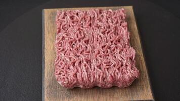 Fresh raw ground minced beef with salt and spices on textured concrete background video