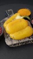 Yellow sweet pepper cut in half and grilled with salt, spices and herbs on a dark concrete background video
