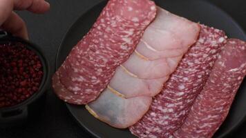 Delicious fresh smoked sausages cut with slices on a dark concrete background video