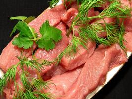 Raw uncooked meat with greens on a plate close view background photo