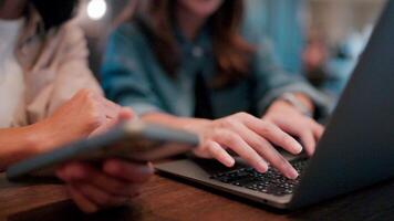 Laptop and Smartphone. Two women, in a casual setting, collaborate on a project. The focus is on the hands, one typing on a laptop keyboard and the other holding a smartphone. video
