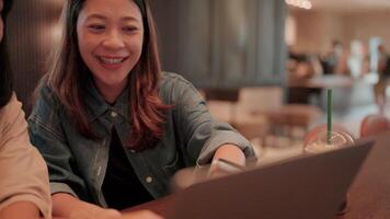Cafe Collaboration. Two young women, engrossed in a laptop, share a moment of focused collaboration in a cozy cafe setting. The image captures a sense of shared purpose and modern workstyle. video