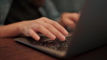 Hands Typing on Laptop. Close-up shot of hands diligently typing on a laptop keyboard, showcasing focus and productivity in a dimly lit setting. video