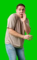Man expressing fear while standing against a bright green background photo