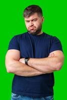 Man expressing confusion with crossed arms in front of a bright green background photo