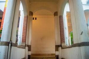 Historic arched corridor with brick and plaster columns, showcasing classic architectural design and serene ambiance. Ideal for capturing timeless beauty in urban photography photo