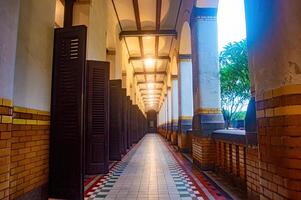 A beautifully lit corridor with arched ceilings, wooden shutters, and a patterned tile floor, showcasing architectural elegance photo
