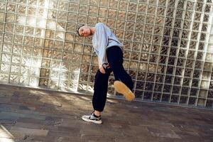A young man dances in front of a glass block wall, showcasing his unique style and impressive moves photo