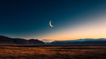 Vast landscape under a crescent moon at dusk with mountains in the background photo