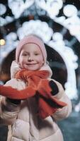 The girl is happy about the New Year. The child smiles and waves at the camera against the background of a beautiful Christmas decoration. Neon lights. video