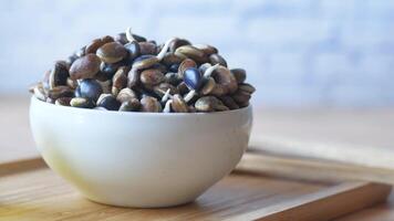 A wooden tray holds a bowl of assorted seeds and crunchy nuts video