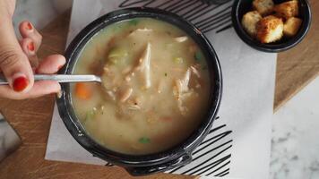 A Bowl of Warm Chicken Soup with Croutons in a Cozy Rustic Setting video