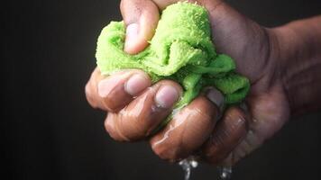 slow motion of Hands squeeze wet towel against black background. draining water from wet towel.. video