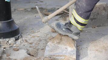A laborer is actively utilizing a pickaxe on a construction site video