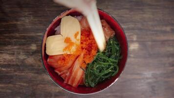 Top view of a person using chopsticks to eat asian bowl. Poke bowl with salmon, rice, avocado, wakame salad, onion. Japanese food style. The concept of proper nutrition and health. video