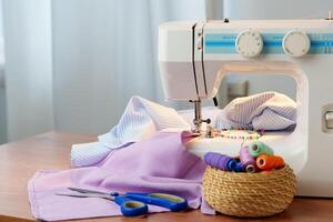 Sewing machine in use on a wooden table, stitching a light fabric in a well-lit indoor workspace photo