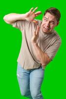 Man expressing fear while standing against a bright green background photo