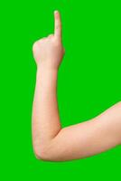 A hand raised with an index finger pointing upwards against a bright green background photo