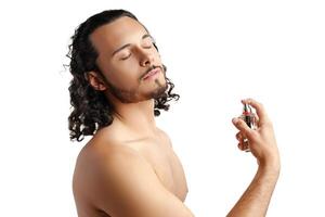 A young man with curly hair applying fragrance after a shower while smiling at the camera photo