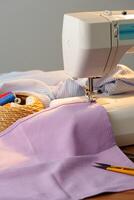 Sewing machine in use on a wooden table, stitching a light fabric in a well-lit indoor workspace photo