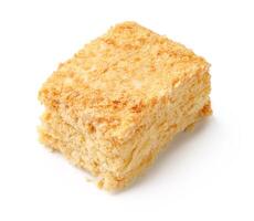 Delicious square of layered dessert made from cream, sugar, and flaky pastry enjoyed in a cozy cafe setting photo