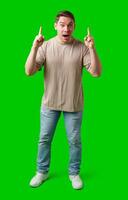 Enthusiastic man pointing upwards against a vibrant green background photo