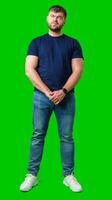 Man standing with a thoughtful expression in a casual outfit against a green background photo