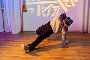 A dancer practices a breakdancing move on a wood floor in a studio photo