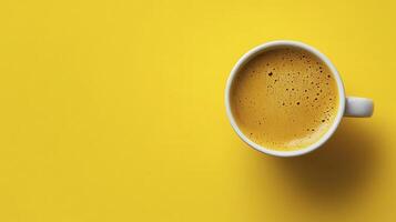 Bright yellow cup of steaming turmeric latte on a vibrant yellow background photo
