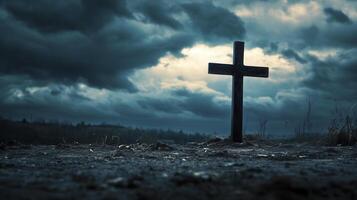 A solitary cross stands against a dramatic sky filled with dark clouds at dusk in a remote outdoor setting photo