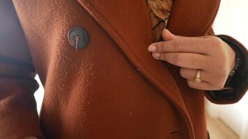 Person Using Lint Roller on a Rust-Colored Coat for Cleaning Purposes video