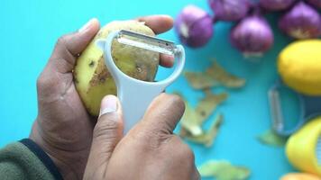 The process of hand peeling a fresh potato is done using a vegetable peeler video