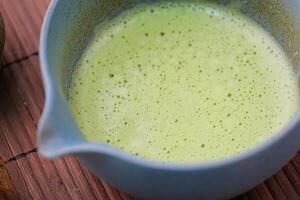 closeup of green matcha tea whipped in the tea bowl photo