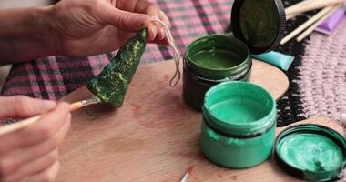 POV hands craft unique Christmas decorations using easy-to-find materials. How to paint Christmas tree shaped craft using paintbrush and green paint of two tones. Holiday DIY craft project video