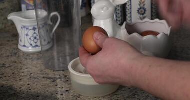 Hands break egg with knife and separate whites from yolks closeup in cooking cup. Chef prepare eggs for cooking. Kitchen space in background, camera move up. Cooking recipe step by step video